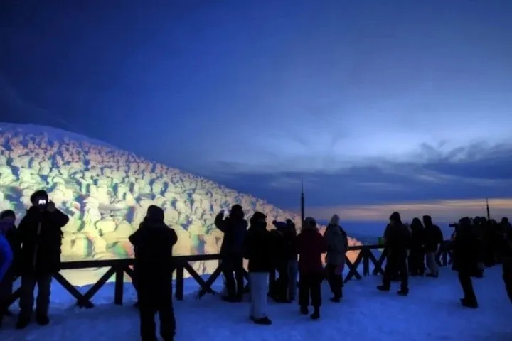Visitors on a lit viewing deck in front of snow-covered rime trees, the Zao snow monsters, at night
