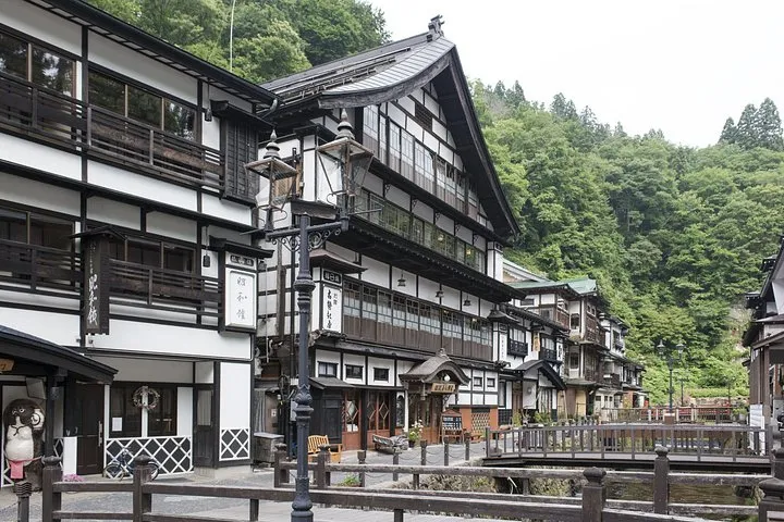 Three-storey wooden ryokan along the river at Ginzan Onsen on a green summer day