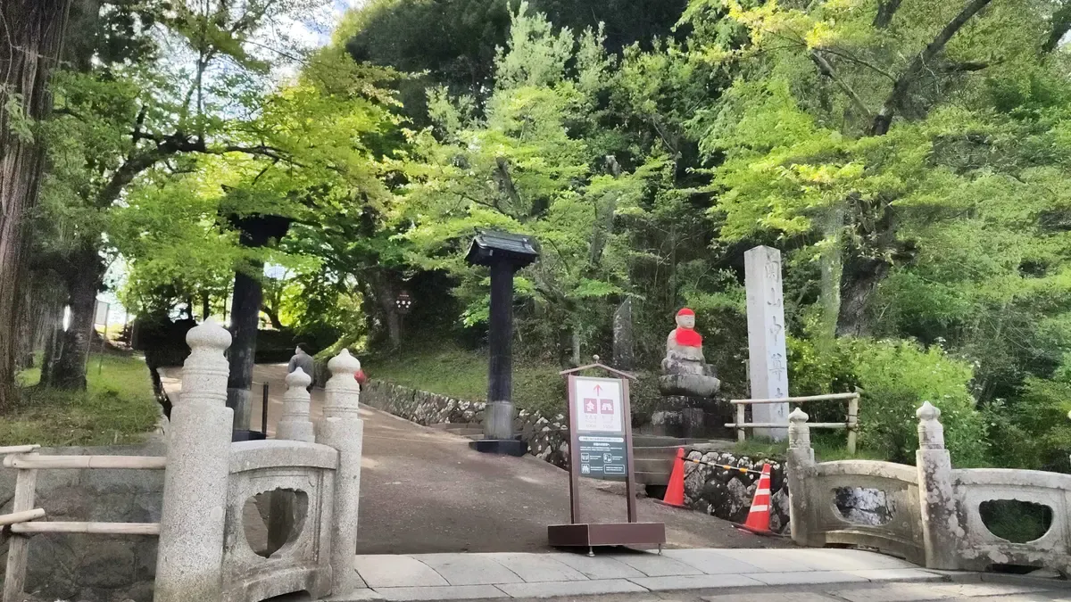 Stone bridge railing and a shaded path at the Chusonji approach