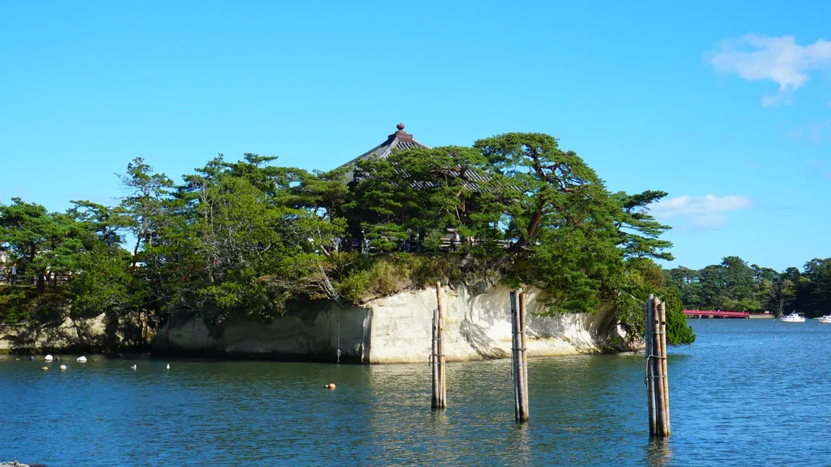 Small hall on a pine-topped rock island in blue water