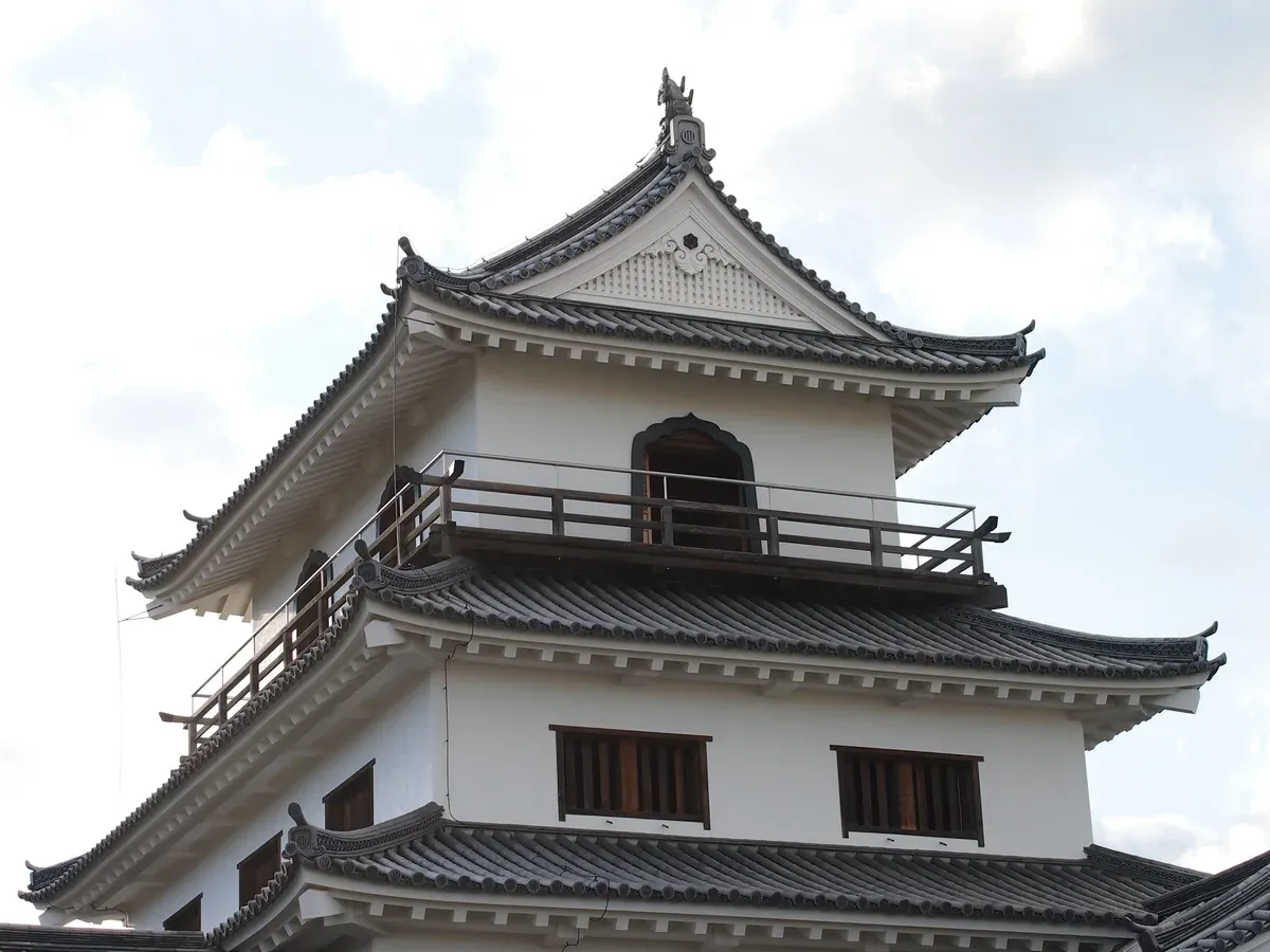 White three-tier castle keep seen from below against a pale sky