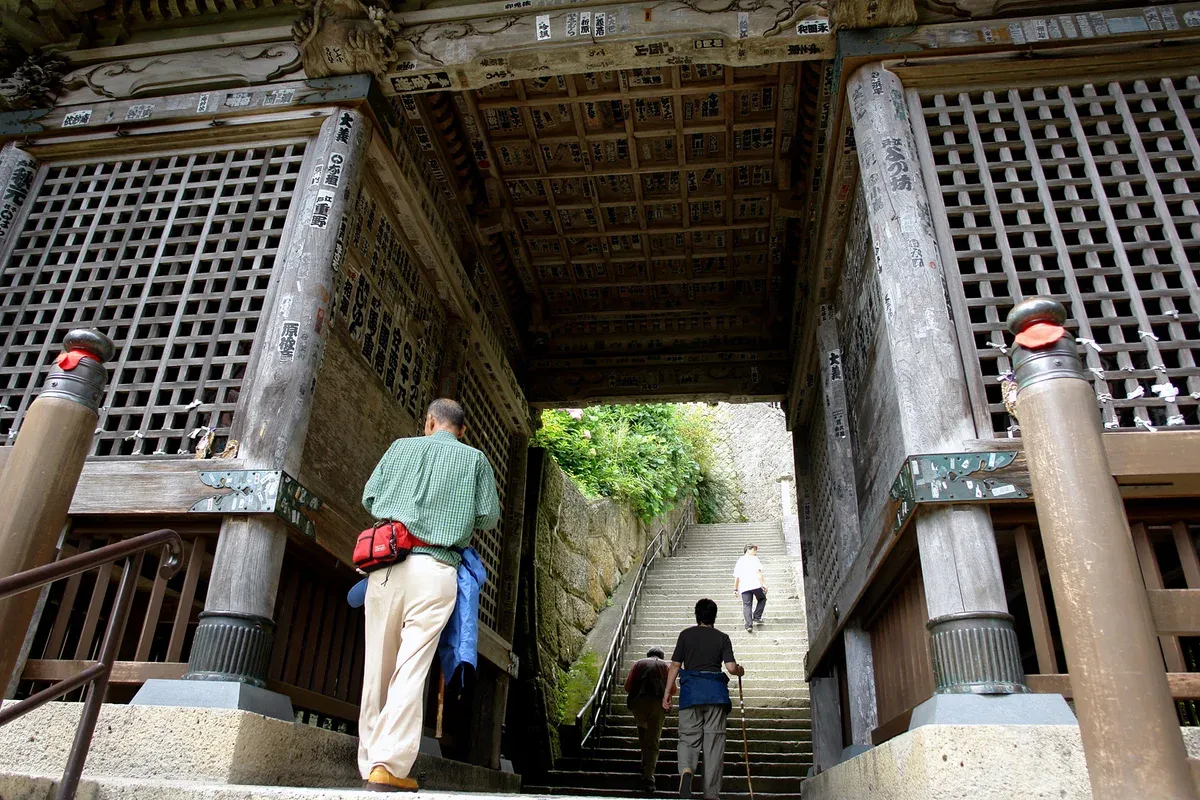 Visitors passing under the old wooden Nio gate at the foot of the stone steps