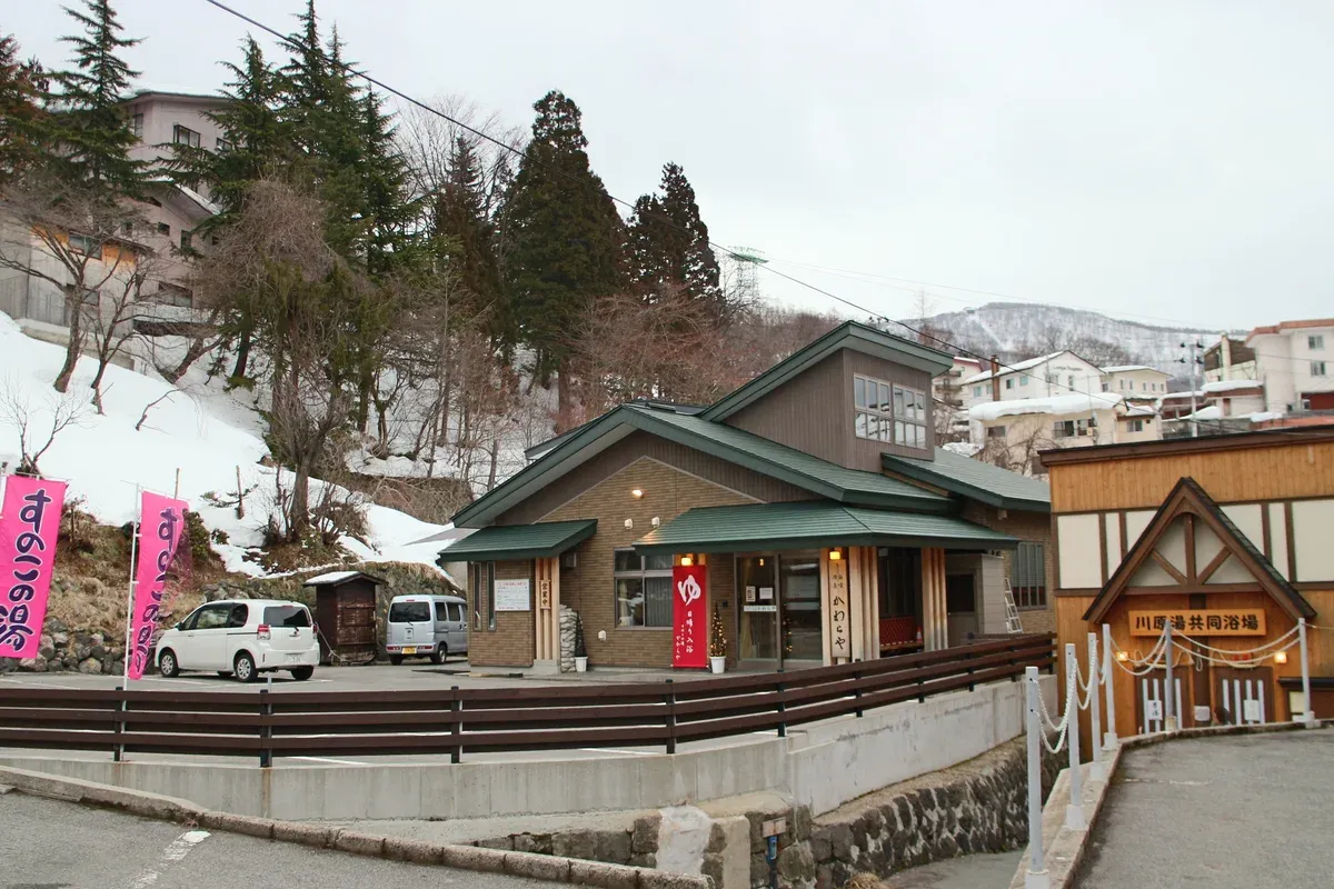 Wooden bathhouse and snow-lined street in Zao Onsen town