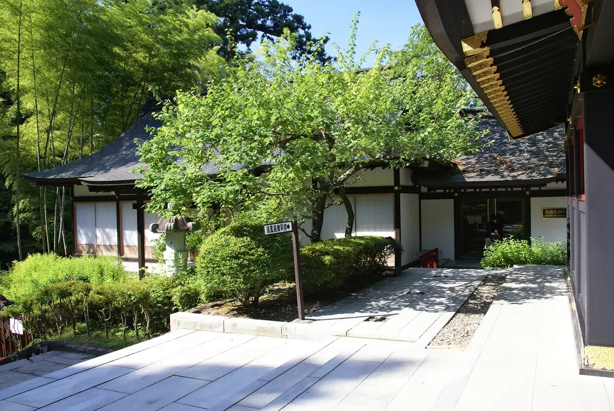 Sunlit courtyard with bamboo and a tiled hall at the Zuihoden mausoleum complex